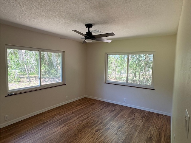 unfurnished room with a textured ceiling, dark wood finished floors, ceiling fan, and a healthy amount of sunlight