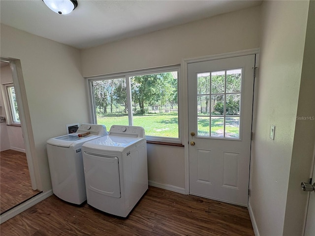 clothes washing area with baseboards, dark wood-style flooring, washer and clothes dryer, and laundry area