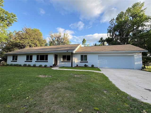 ranch-style house featuring concrete driveway, an attached garage, a front lawn, and stucco siding