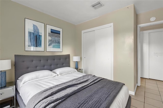 bedroom with a closet, visible vents, baseboards, and light tile patterned floors