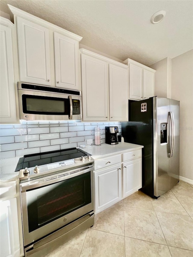 kitchen with backsplash, light countertops, appliances with stainless steel finishes, and white cabinetry