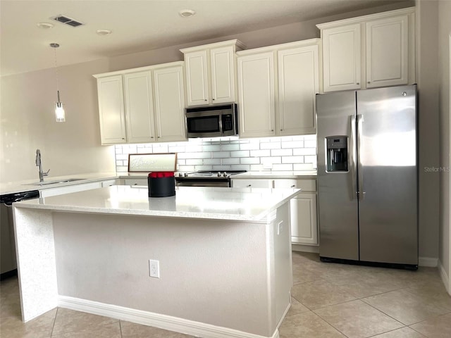 kitchen with tasteful backsplash, a sink, stainless steel appliances, visible vents, and a kitchen island
