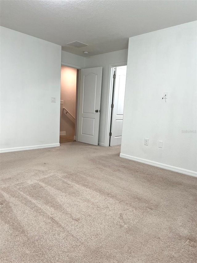 spare room featuring baseboards and light colored carpet