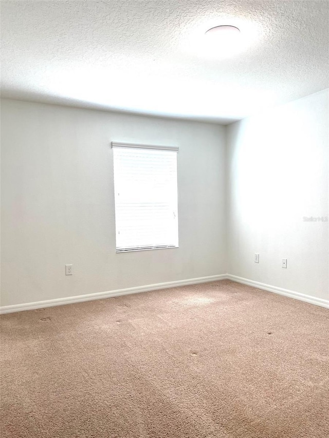 carpeted empty room featuring a textured ceiling and baseboards
