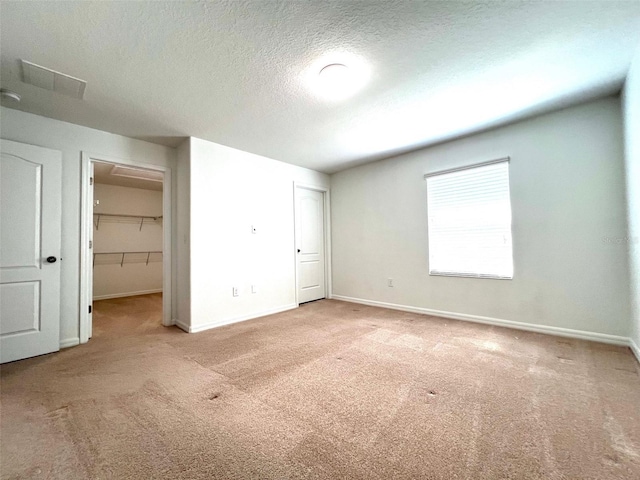 unfurnished bedroom featuring baseboards, visible vents, a textured ceiling, and carpet flooring
