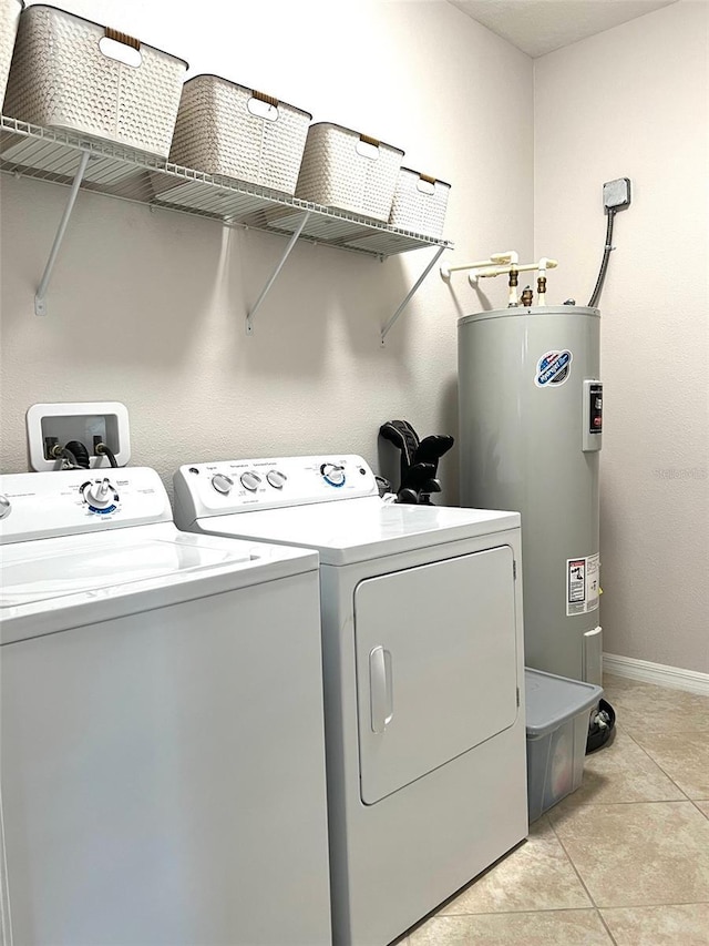 laundry area featuring washing machine and dryer, electric water heater, baseboards, laundry area, and light tile patterned floors
