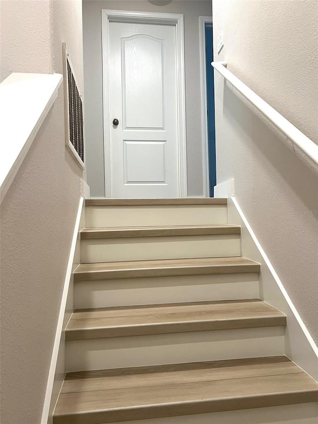 staircase with a textured wall and visible vents