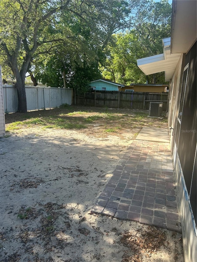 view of yard featuring central AC, fence, and a patio area