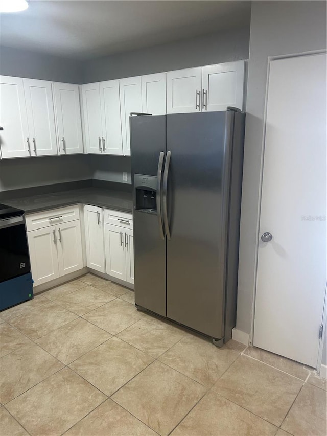 kitchen with electric range, white cabinets, stainless steel refrigerator with ice dispenser, and dark countertops
