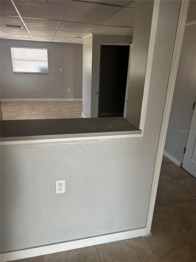 interior space with baseboards and a paneled ceiling
