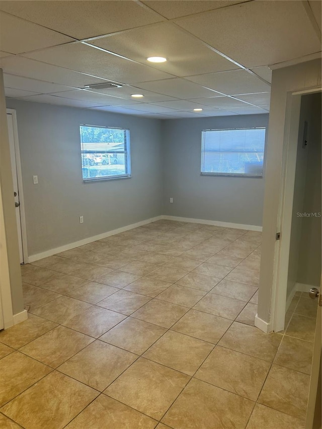below grade area with a paneled ceiling and light tile patterned floors
