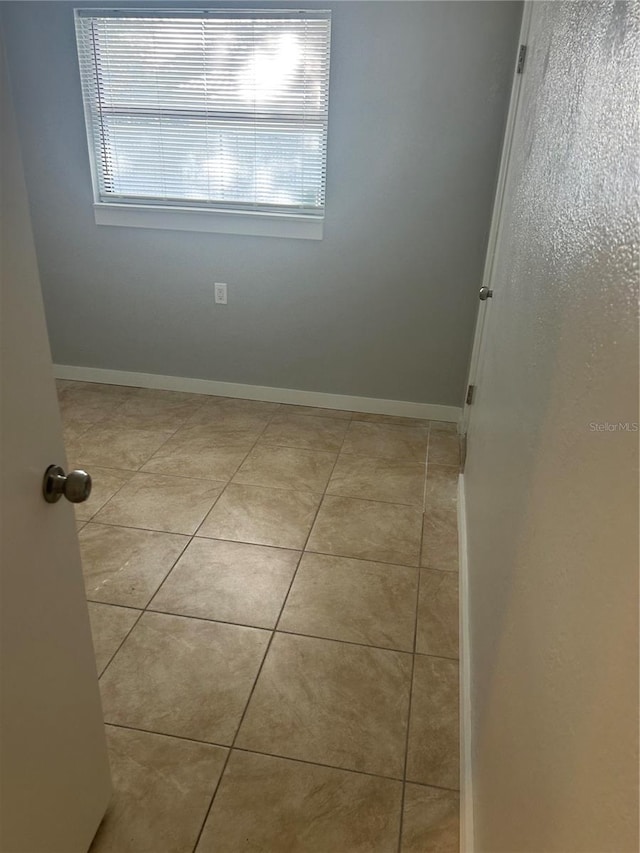unfurnished room featuring baseboards and tile patterned flooring