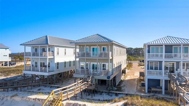 rear view of property featuring stairway, a balcony, and metal roof