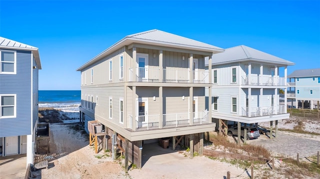 back of house featuring a carport, a balcony, and a water view