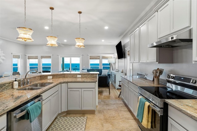 kitchen featuring under cabinet range hood, a sink, light stone countertops, pendant lighting, and appliances with stainless steel finishes