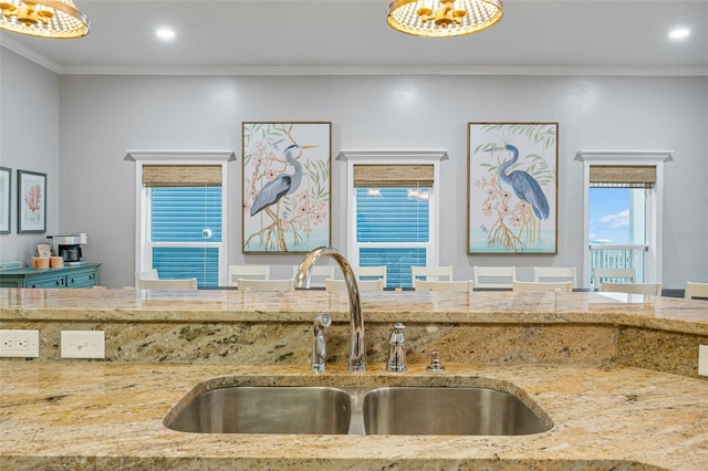 kitchen featuring light stone counters, a sink, recessed lighting, and ornamental molding