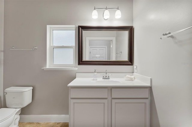 bathroom featuring toilet, vanity, and baseboards