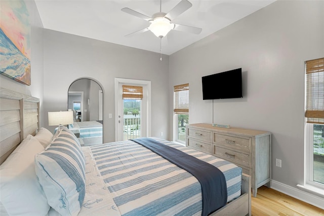 bedroom with light wood-type flooring, multiple windows, baseboards, and access to exterior