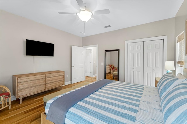 bedroom featuring light wood finished floors, visible vents, a closet, baseboards, and ceiling fan