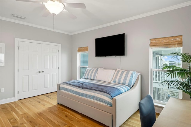 bedroom with visible vents, light wood-style floors, a ceiling fan, a closet, and ornamental molding