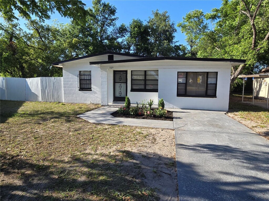 view of front facade with concrete block siding, a front lawn, and fence