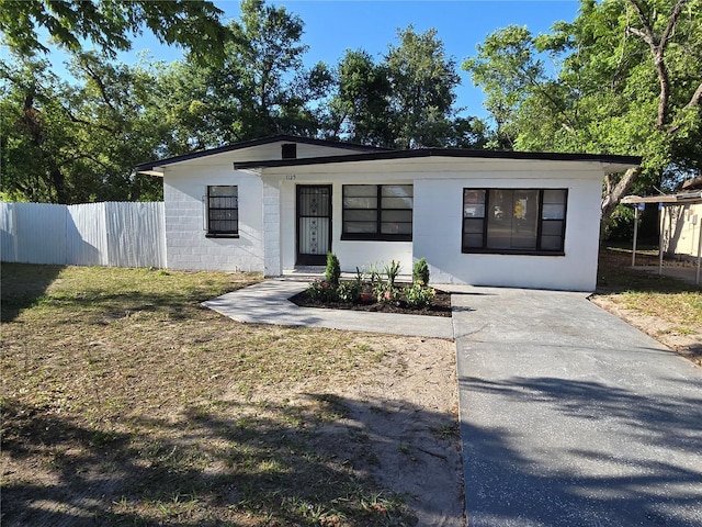 view of front facade with concrete block siding, a front lawn, and fence