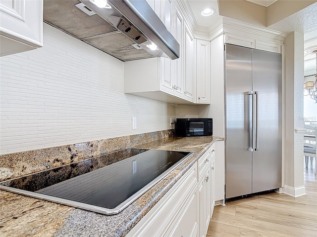 4071 S Atlantic Ave Unit 803, New Smyrna Beach, FL 32169 - kitchen featuring built in fridge, extractor fan, black electric cooktop, light wood finished floors, and white cabinets