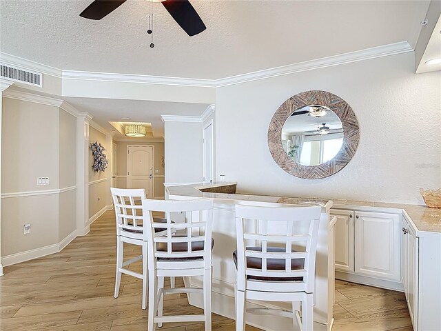 4071 S Atlantic Ave Unit 803, New Smyrna Beach, FL 32169 - dining space featuring ceiling fan, ornamental molding, light wood-style flooring, and a textured ceiling