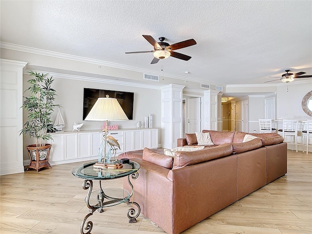 4071 S Atlantic Ave Unit 803, New Smyrna Beach, FL 32169 - living room featuring ceiling fan, light wood-style flooring, ornamental molding, a textured ceiling, and ornate columns