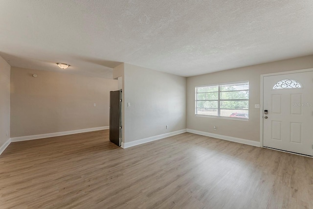 entrance foyer with baseboards, light wood-style flooring, and a textured ceiling