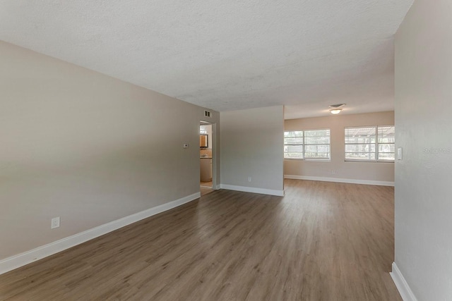 spare room with baseboards, a textured ceiling, and wood finished floors