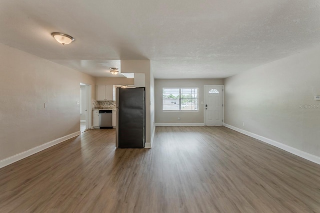 unfurnished living room with baseboards and wood finished floors