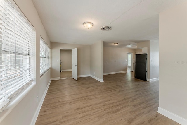 spare room with baseboards, visible vents, a healthy amount of sunlight, and light wood-style floors