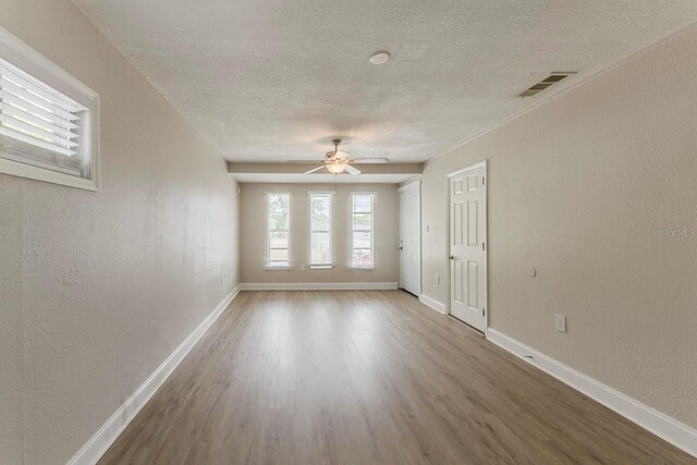 empty room featuring baseboards, wood finished floors, and visible vents