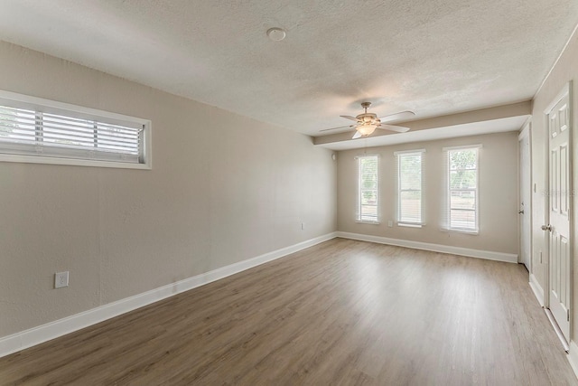 spare room featuring baseboards, a textured ceiling, and wood finished floors