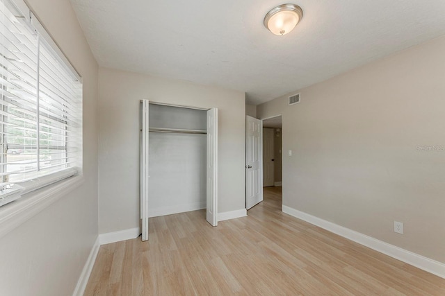 unfurnished bedroom with visible vents, baseboards, a closet, and light wood-type flooring