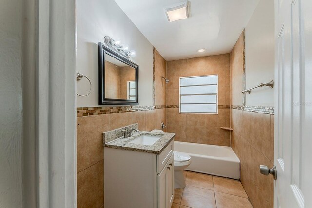 bathroom featuring tile patterned flooring, vanity, toilet, tile walls, and shower / bathing tub combination