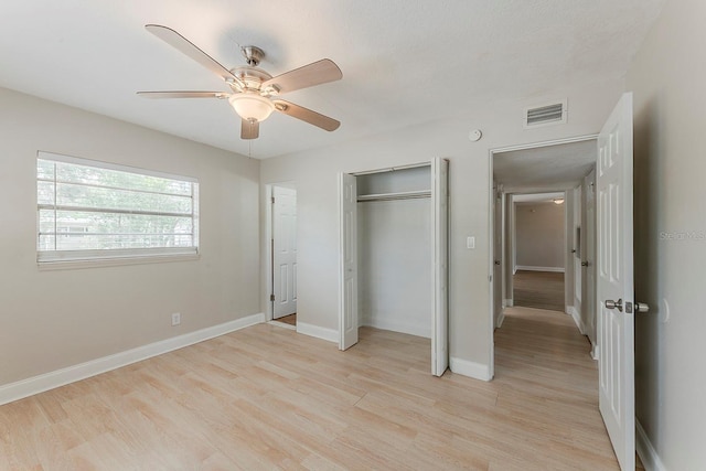 unfurnished bedroom with a closet, baseboards, visible vents, and light wood-type flooring