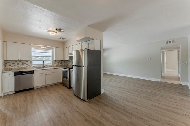 kitchen with light wood-type flooring, a sink, baseboards, and stainless steel appliances