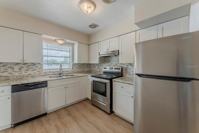 kitchen with a sink, light wood finished floors, stainless steel appliances, under cabinet range hood, and visible vents