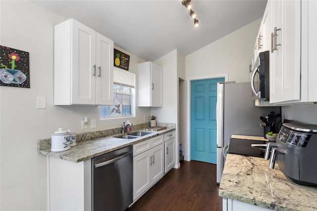 kitchen with vaulted ceiling, a sink, dark wood-style flooring, appliances with stainless steel finishes, and white cabinetry