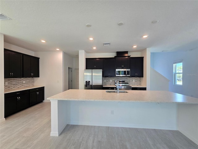 kitchen featuring backsplash, dark cabinets, stainless steel appliances, and visible vents