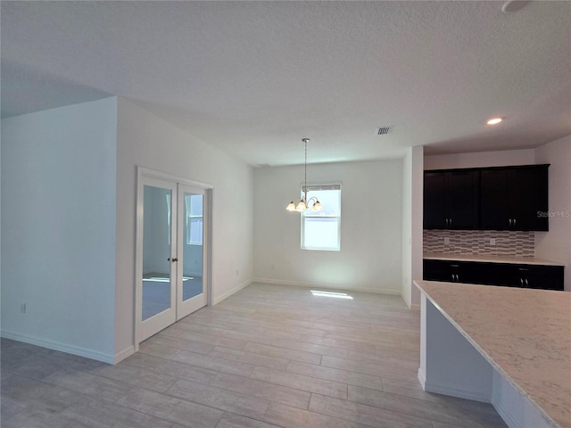 kitchen with french doors, light wood finished floors, baseboards, a notable chandelier, and visible vents