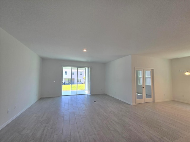 unfurnished living room featuring recessed lighting, baseboards, french doors, and light wood-type flooring