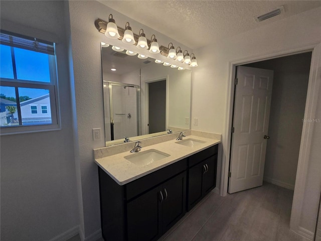 full bathroom featuring a textured ceiling, a shower stall, visible vents, and a sink