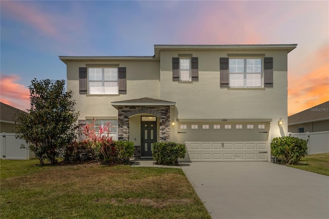 traditional-style home featuring fence, a yard, stucco siding, driveway, and a garage