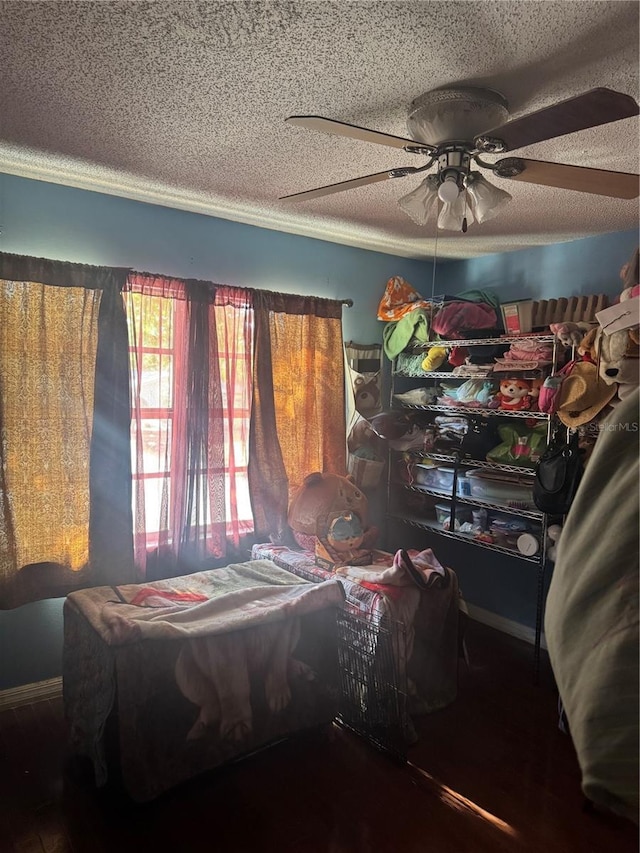 bedroom with baseboards, a ceiling fan, and a textured ceiling