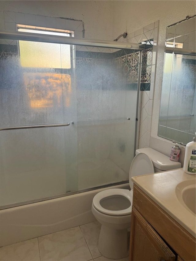 full bathroom featuring toilet, tile patterned floors, combined bath / shower with glass door, and vanity