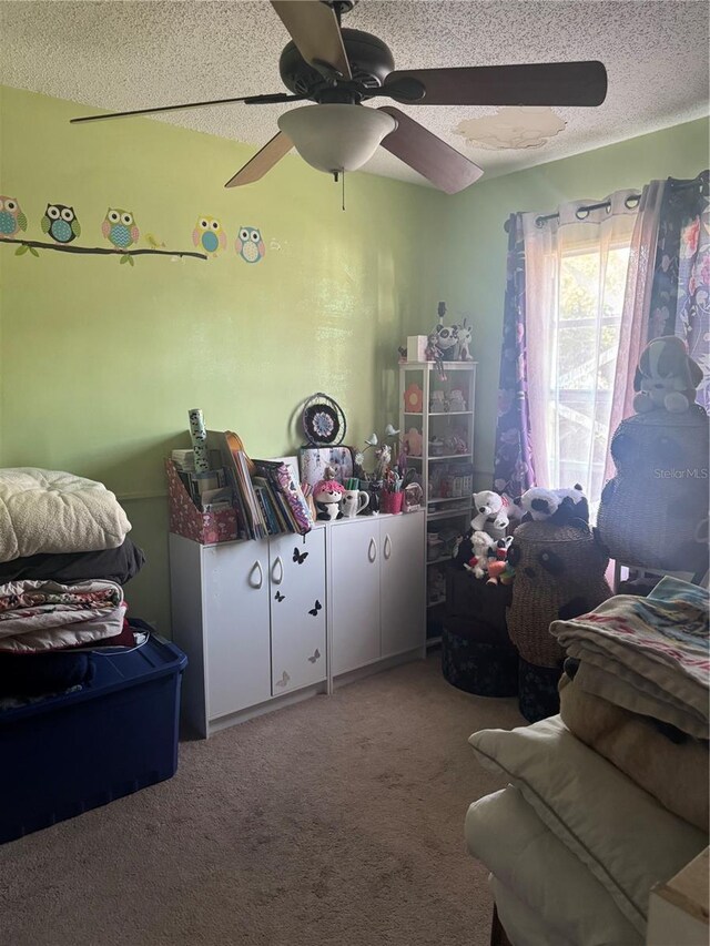 bedroom featuring a ceiling fan, a textured ceiling, and carpet