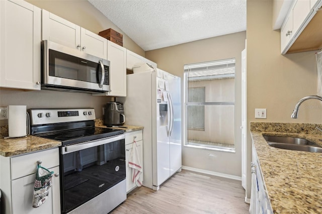 kitchen featuring a sink, a textured ceiling, light wood-style floors, white cabinets, and appliances with stainless steel finishes
